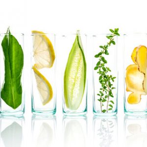 Fünf Gläser nebeneinander mit verschiedenen Obst- und Kräutersorten bestückt
